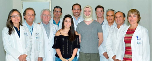 Toma frontal del equipo de doctores del Centro de Cirugía Plástica. En frente de ellos, dos pacientes sonríen a la cámara.
