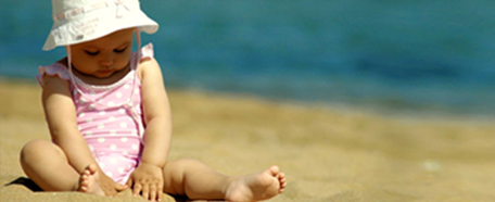 Niña pequeña juega en la playa con arena