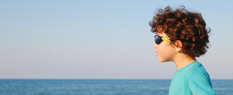 Niño con lentes de sol viendo el mar