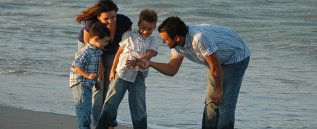 Padre, madre y sus dos hijos pequeños recorren la playa