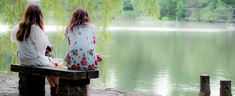 Dos mujeres sentadas contemplando las aguas de un lago