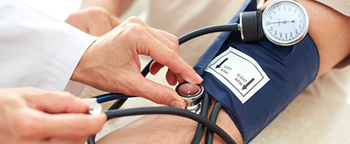 Doctor le mide la presión arterial a un paciente