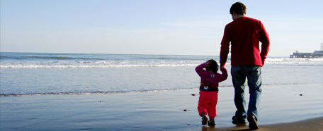 Hombre junto a su hijo pequeño recorren la playa