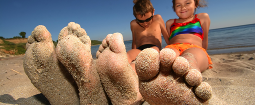 Pareja de hermanos juega con sus pies en la arena de una playa