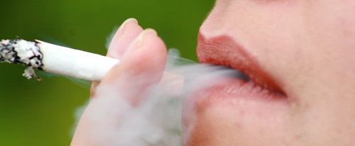 Close up de los labios de una mujer que fuma y expira  humo