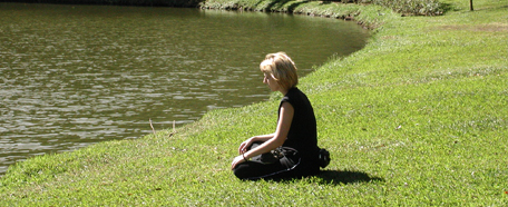 Mujer sentada en el pasto contempla un lago