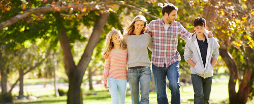 una familia  compuesta  por un hijo y una hija adolescente caminan por el parque