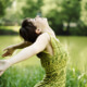 Mujer con vestido verde gesticula júbilo, en medio de la naturaleza