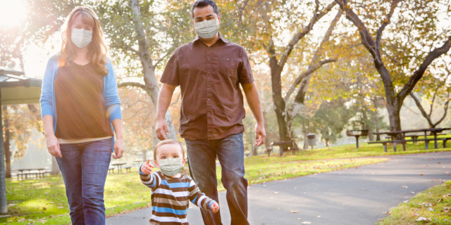 familia con mascarilla paseando por el parque con su hijo