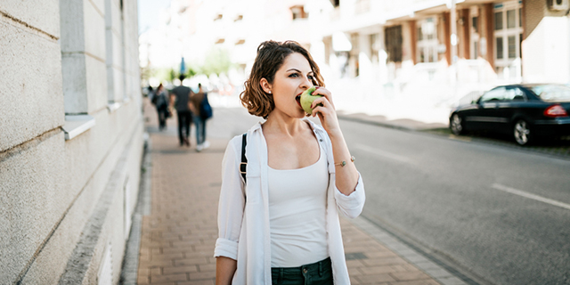Mujer recorre la ciudad comiendo una manzana
