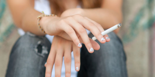 Manos de una adolescente con un cigarro