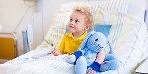 Niño sonriendo en cama del hospital con un peluche