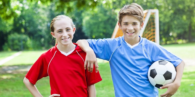 Dos adolescentes sonriendo en una cancha de fútbol