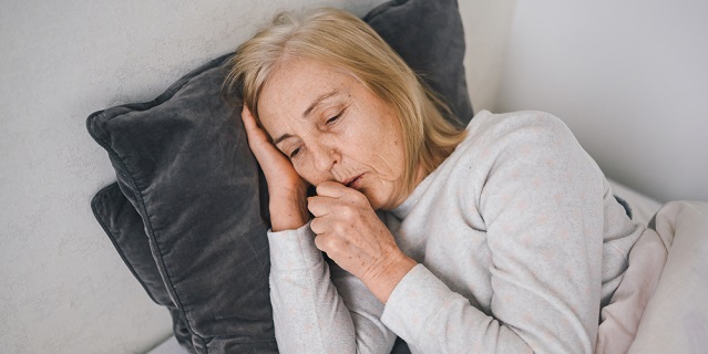Anciana tosiendo en su cama