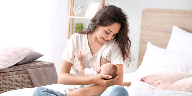 Mujer joven amamantando a su bebé en casa