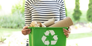Mujer sosteniendo un recipiente con basura para reciclar