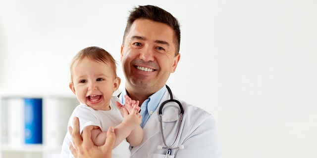 Doctor pediatra sosteniendo a un niño en su consulta