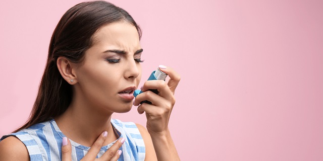 Mujer joven obstruida utilizando inhalador por ataque de asma