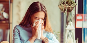 Mujer estornudando con síntomas de coronavirus