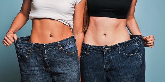 Dos mujeres mostrando que le quedan grandes sus pantalones tras someterse a operación bariátrica