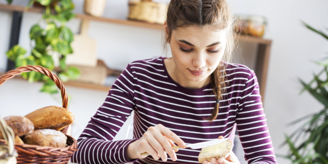Mujer joven untando mantequilla en pan