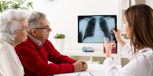 doctora mostrando a pareja de adultos mayores una radiografía de pulmón