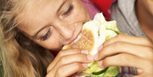 Adolescente mujer come una hamburguesa