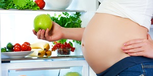 Mujer embarazada frente al refrigerador