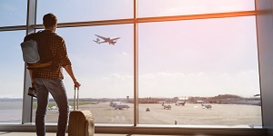 Hombre con maleta viendo cómo despega un avión 