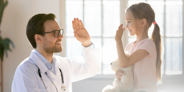 doctor con niña chocando las manos