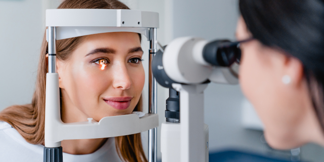 Médico oftalmológico con paciente mujer durante un examen en clínica moderna
